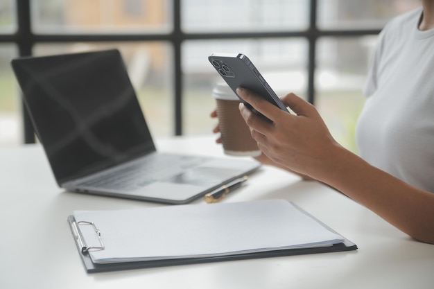 Donna d'affari asiatica Utilizzando il computer portatile e lavorando in ufficio con il documento della calcolatrice sulla scrivania facendo pianificazione analizzando il concetto di analisi finanziaria di investimento del piano aziendale della relazione finanziaria