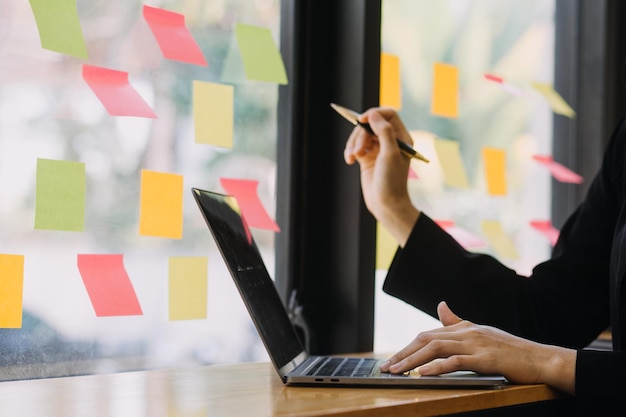 Donna d'affari asiatica Utilizzando il computer portatile e lavorando in ufficio con il documento della calcolatrice sulla scrivania facendo pianificazione analizzando il concetto di analisi finanziaria di investimento del piano aziendale della relazione finanziaria