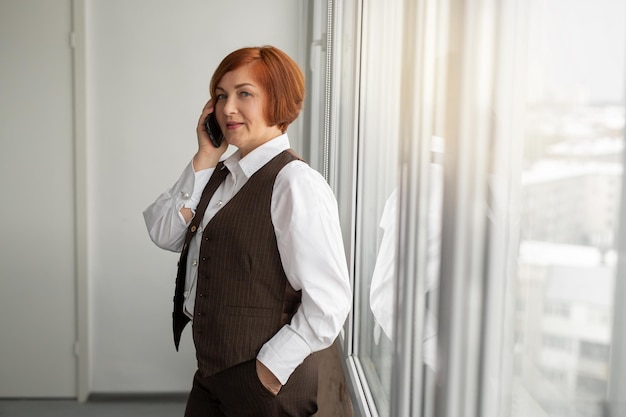 donna d'affari caucasica adulta in giacca e cravatta chiama il telefono in ufficio