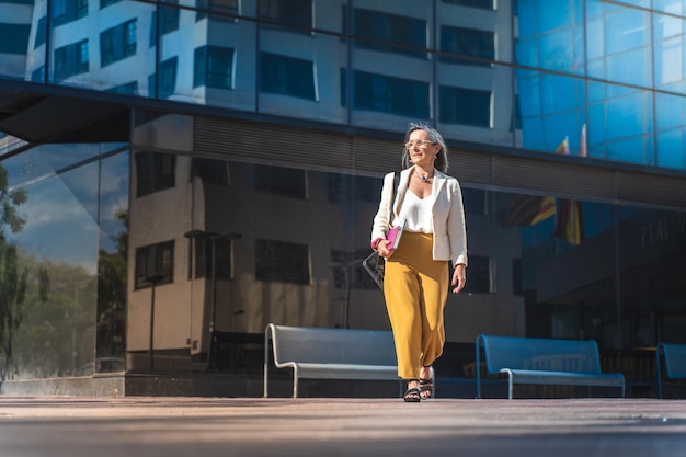 Donna d'affari che cammina in una città moderna elegante con computer portatile e tecnologia