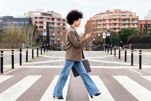Donna d'affari che cammina su un passaggio pedonale tramite telefono