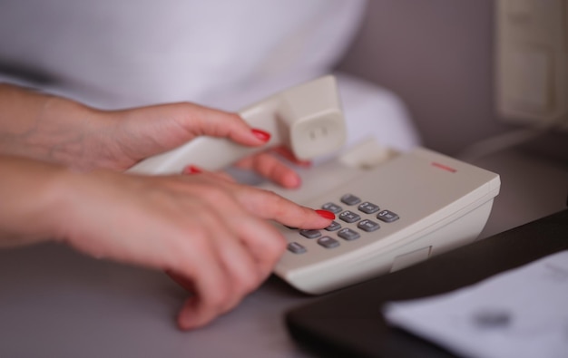 Donna d'affari che chiama un numero di telefono in una stanza d'albergo.