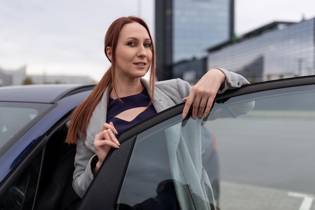 Donna d'affari che esce dall'auto sullo sfondo di un edificio per uffici