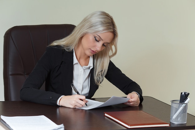 Donna d'affari che firma un contratto o un documento in una scrivania in ufficio