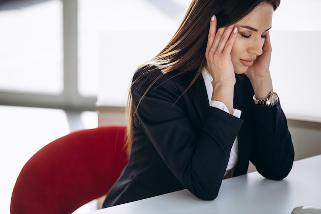 Donna d'affari che ha mal di testa in un posto di lavoro