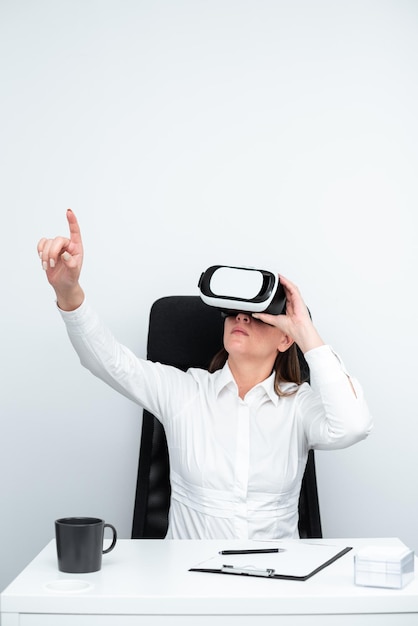 Donna d'affari che indossa occhiali per realtà virtuale e apprende abilità professionali attraverso una simulazione futuristica Donna che gesticola mentre è seduto alla scrivania durante la formazione moderna