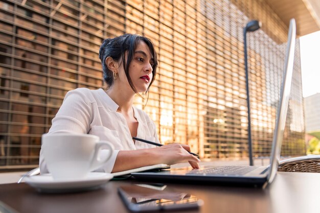 Donna d'affari che lavora con il suo computer sulla terrazza di una caffetteria nel distretto finanziario, concetto di imprenditore digitale e stile di vita urbano