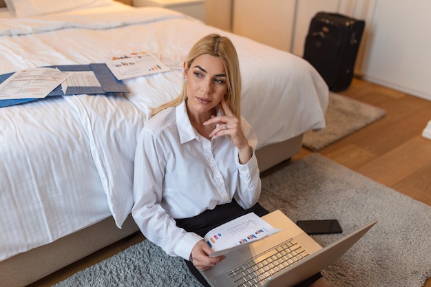 Donna d'affari che lavora da una camera d'albergo. Bella giovane donna che pensa a nuove idee imprenditoriali. Seduto per terra a lavorare a tarda notte