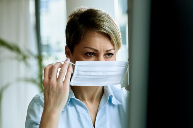 Donna d'affari che lavora in ufficio e indossa una maschera facciale come protezione