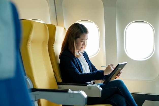Donna d'affari che lavora su tablet mentre è seduto in aereo