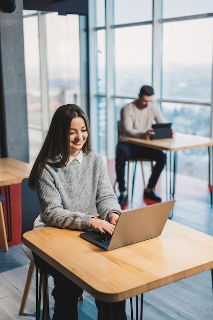 Donna d'affari che lavora su un progetto online che guarda il portatile sul posto di lavoro professionale in ufficio seduta alla scrivania con il computer lavoro moderno online in ufficio caffè