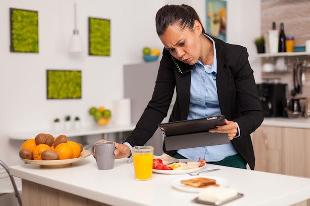 Donna d'affari che legge una brutta notizia sul suo tablet mentre fa colazione