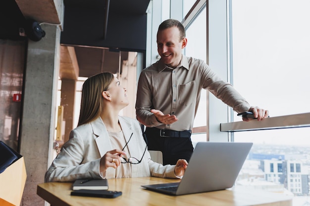 Donna d'affari che punta il dito verso un laptop per un collega di sesso maschile Cooperazione commerciale e lavoro di squadra Millennial europei al tavolo in ufficio Persone moderne di successo