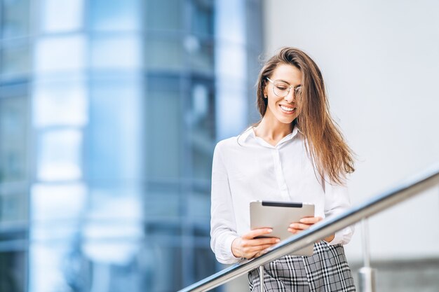 Donna d'affari che utilizza tablet vicino al moderno centro business.