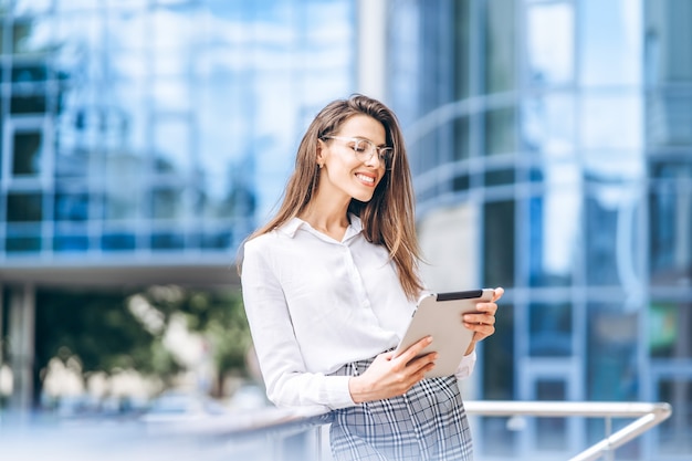 Donna d'affari che utilizza tablet vicino al moderno centro business.