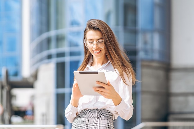 Donna d'affari che utilizza tablet vicino al moderno centro business.