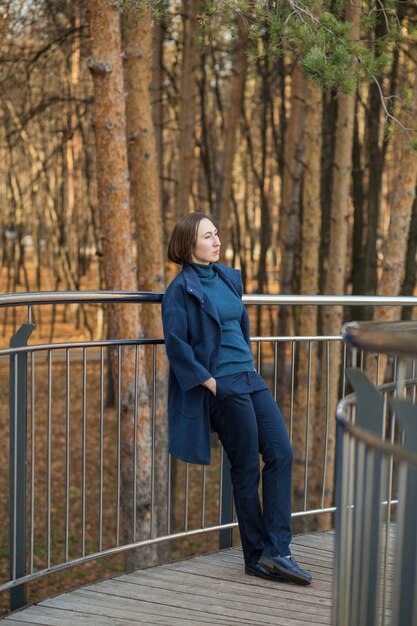 donna d'affari con il cappotto blu sul ponte nella città d'autunno