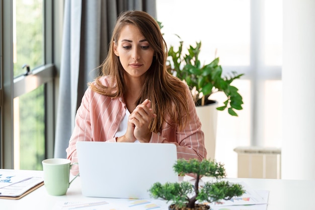 Donna d'affari concentrata che usa il laptop a casa guardando lo schermo in chat leggendo o scrivendo e-mail seduta sul divano studentessa che fa i compiti lavorando su un progetto di ricerca online