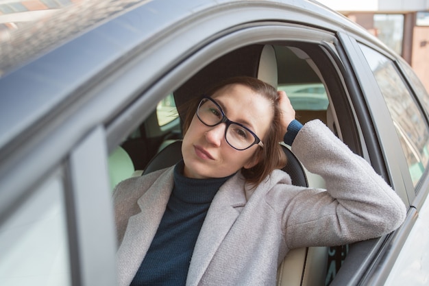 Donna d'affari di moda in bicchieri alla guida di auto.