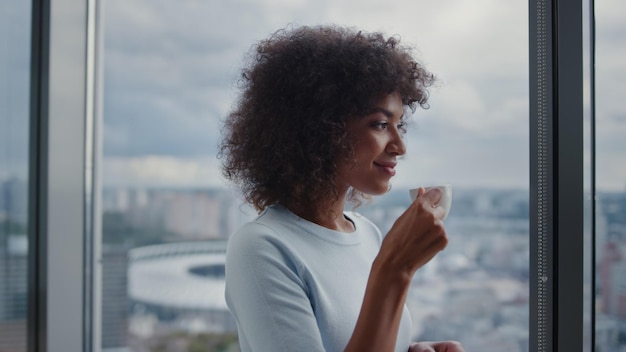 Donna d'affari di razza mista che beve caffè sulla vista della città Esecutivo che prende una pausa