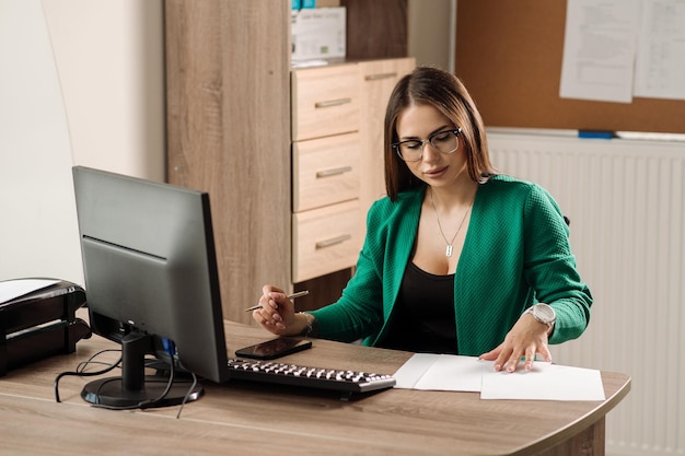 Donna d'affari di successo ben vestita che lavora al computer nella stanza dell'ufficio