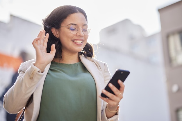 Donna d'affari e telefono con videochiamata in città e contatto con comunicazione o conversazione di connessione di rete Onda felice e persona che parla sul cellulare o ciao gesto e saluto