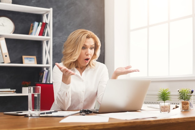 Donna d'affari emotiva che lavora al computer portatile in ufficio