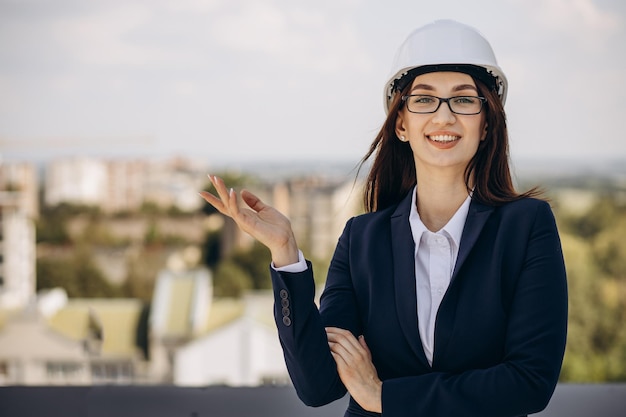Donna d'affari in casco bianco in piedi sul tetto dell'edificio