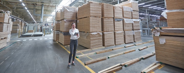 Donna d'affari in fabbrica di carpenteria industriale - produzione di tavole di legno con macchine moderne