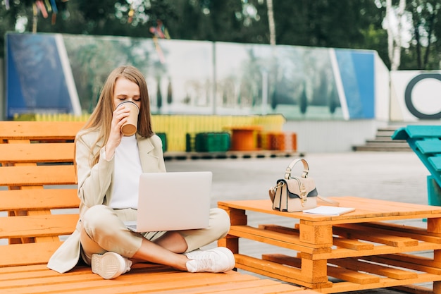 Donna d'affari in giacca sportiva che lavora al computer portatile all'esterno