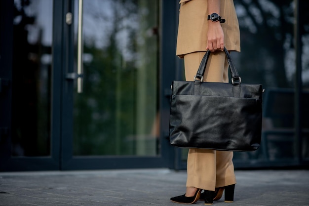 Donna d'affari in possesso di una borsa per laptop andando in ufficio Visualizzazione di imprenditrice su edifici moderni della città