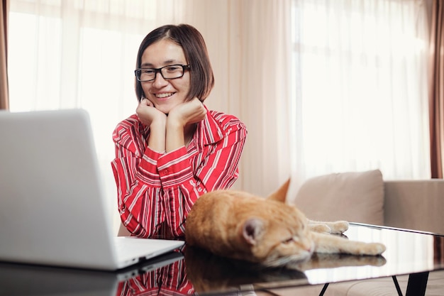 Donna d'affari in una camicia rossa con un gatto zenzero a casa