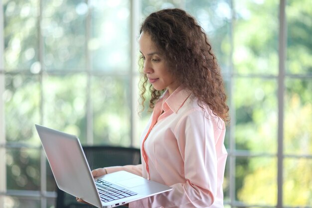 Donna d'affari latina che lavora su un laptop in ufficio.