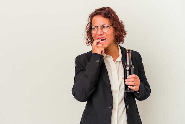 Donna d'affari latina di mezza età in possesso di una birra isolata su sfondo bianco rilassato pensando a qualcosa guardando uno spazio di copia.