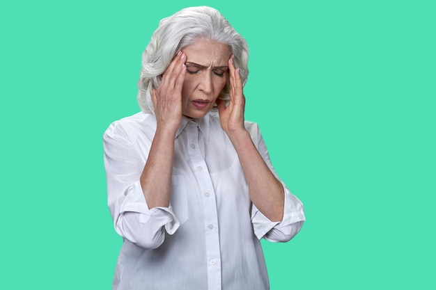 Donna d'affari matura che soffre di emicrania su sfondo colorato nonna con forte mal di testa