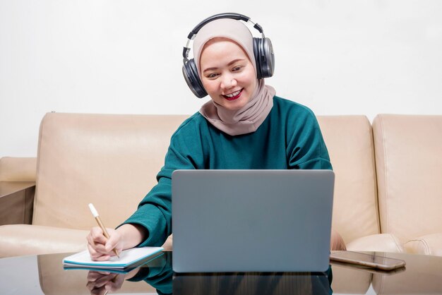 Donna d'affari musulmana asiatica che utilizza un computer portatile che lavora da casa. Prevenire la malattia influenzale Coronavirus