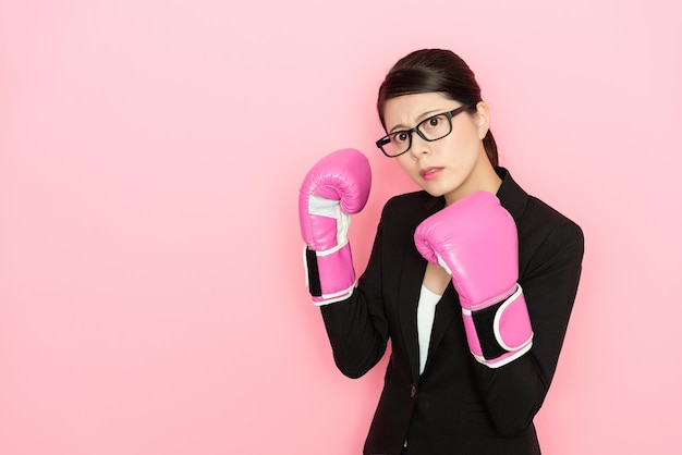 donna d'affari pronta a combattere indossando i guantoni da boxe isolati su sfondo rosa