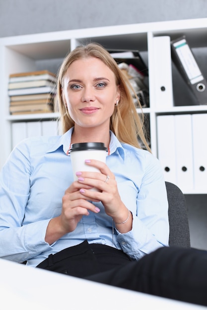 Donna d'affari sorridente che beve caffè da un bicchiere di carta