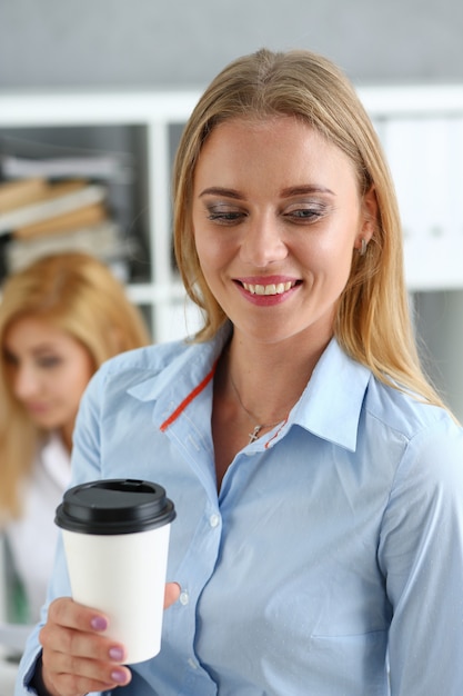 Donna d'affari sorridente che beve caffè da un giornale