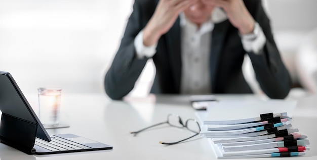 Donna d'affari stanca e stressata con una pila di documenti sul tavolo Concetto di stress professionale