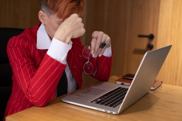 Donna d'affari stanca, stressata, lavora al portatile, mal di testa.