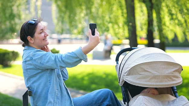Donna dai capelli castani che fa selfie durante la passeggiata nel parco con il bambino