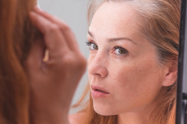 Donna dai capelli grigi che guarda la riflessione in morror