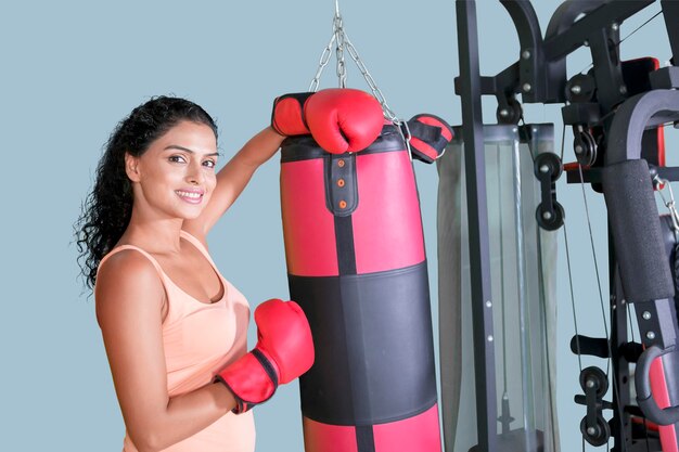 Donna dai capelli ricci appoggiata a una borsa da boxe