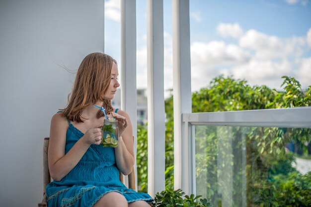 Donna dai capelli rossi che beve un mojito sulla terrazza