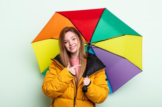 Donna dai capelli rossi che sembra eccitata e sorpresa che indica il concetto di ombrello laterale