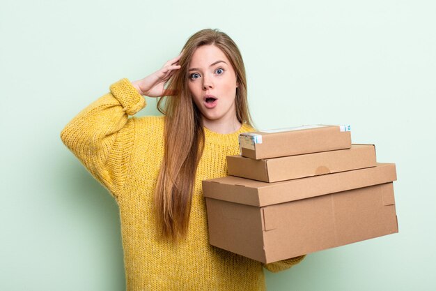 Donna dai capelli rossi che sembra felice, stupita e sorpresa, il concetto di scatole di pacchetti