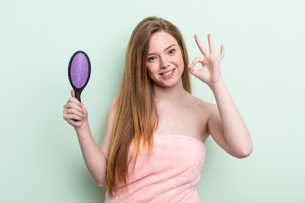 Donna dai capelli rossi che si sente felice, mostra approvazione con un gesto ok. concetto di pettine per capelli