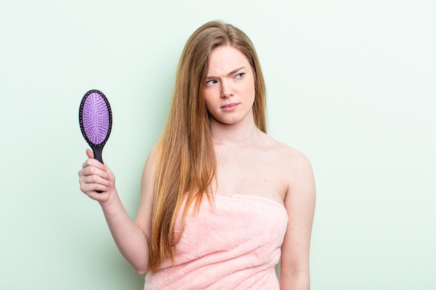 Donna dai capelli rossi che si sente triste sconvolta o arrabbiata e guarda al concetto di pettine per capelli laterale