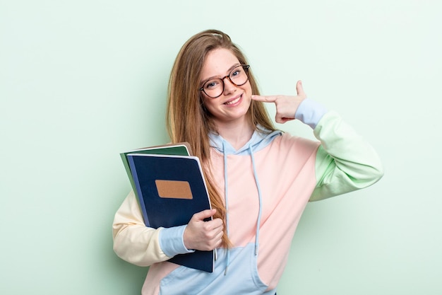 donna dai capelli rossi che sorride con sicurezza indicando il proprio ampio sorriso. concetto di studente